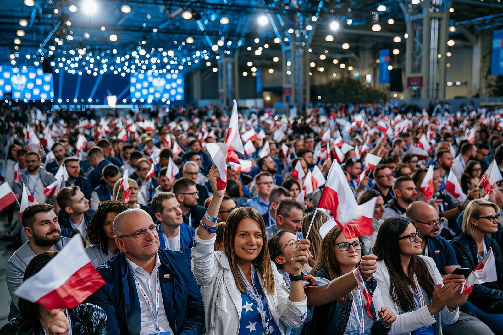 Zsúfolásig megtelt kiállítóterem, ahol kis zászlókat lengettek erős rendezvényvilágítás mellett az AfD magdeburgi kampányindítóján, a távolban egy színpaddal.