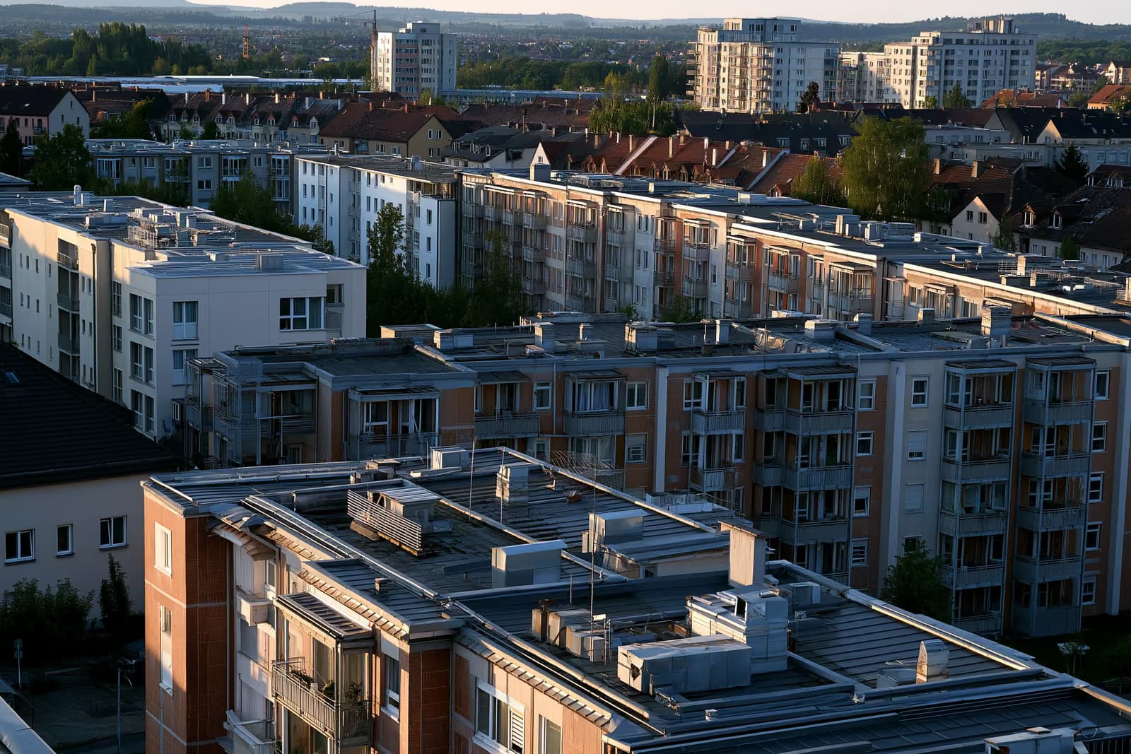 Lakóépületek háztetői és fűtőnyílásai egy német városban meleg délutáni fényben.
