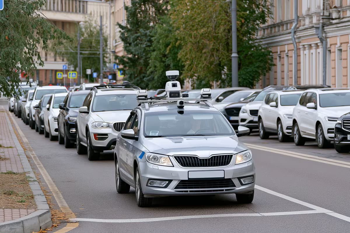 Egy kamerával felszerelt városi autó pásztázza a parkoló járműveket egy városi utcán.
